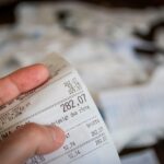 Anziano che consulta una bolletta con espressione pensierosa, riflettendo su come risparmiare.